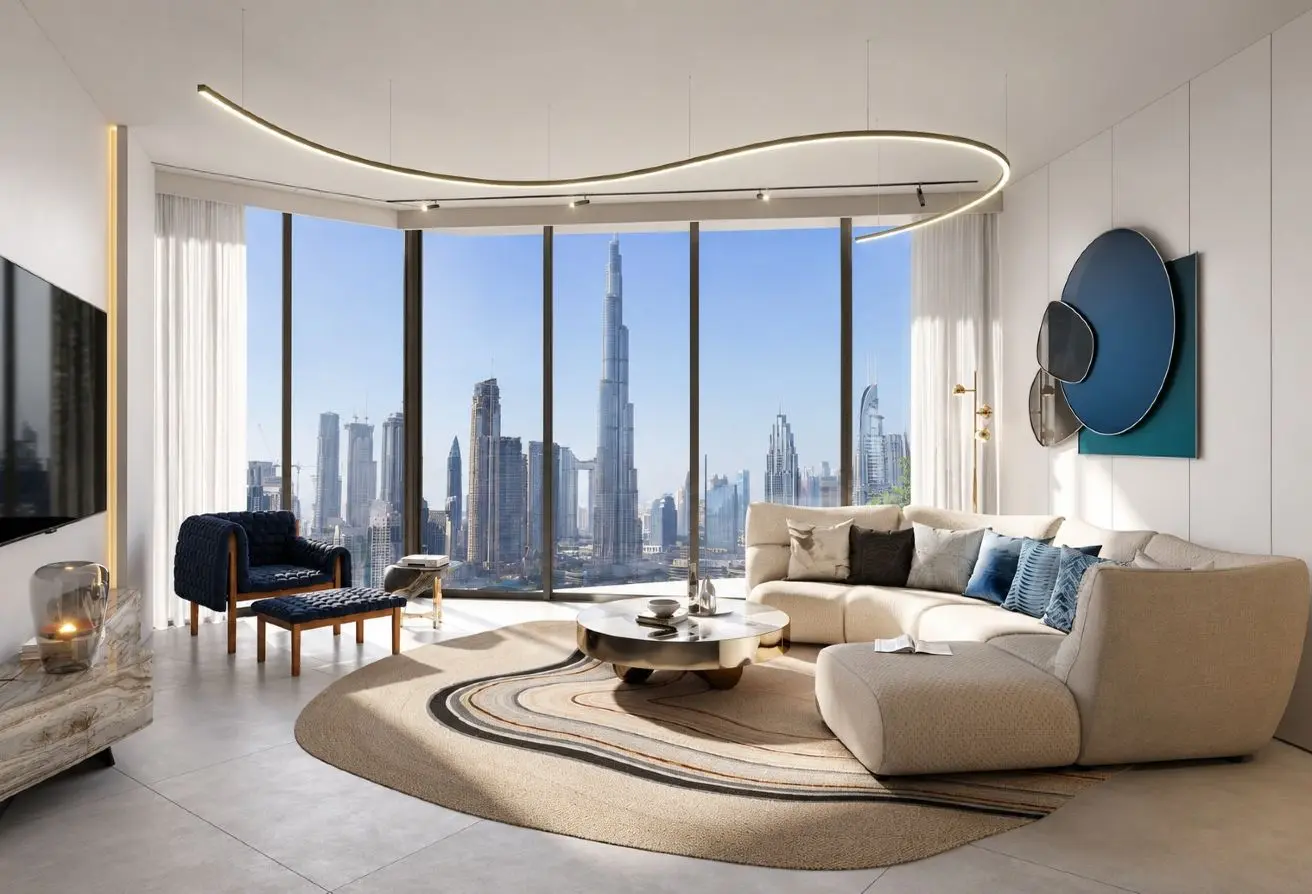 Bright contemporary living room with a curved beige sectional, circular rug, and floor-to-ceiling windows showing a city skyline.