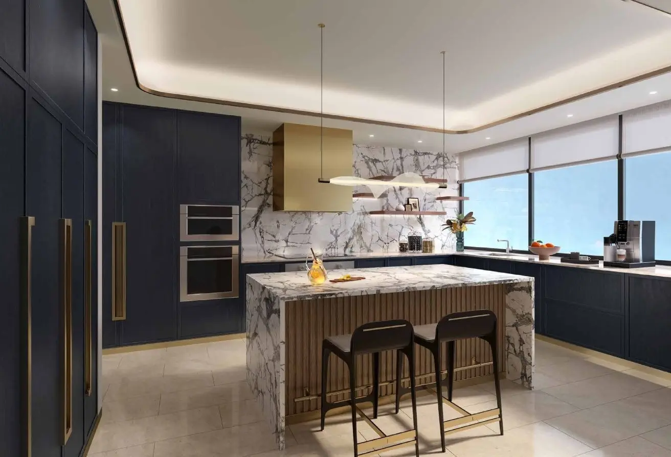 Modern luxury kitchen with navy cabinets, marble island, and gold barstools under a tray ceiling with pendant lights.
