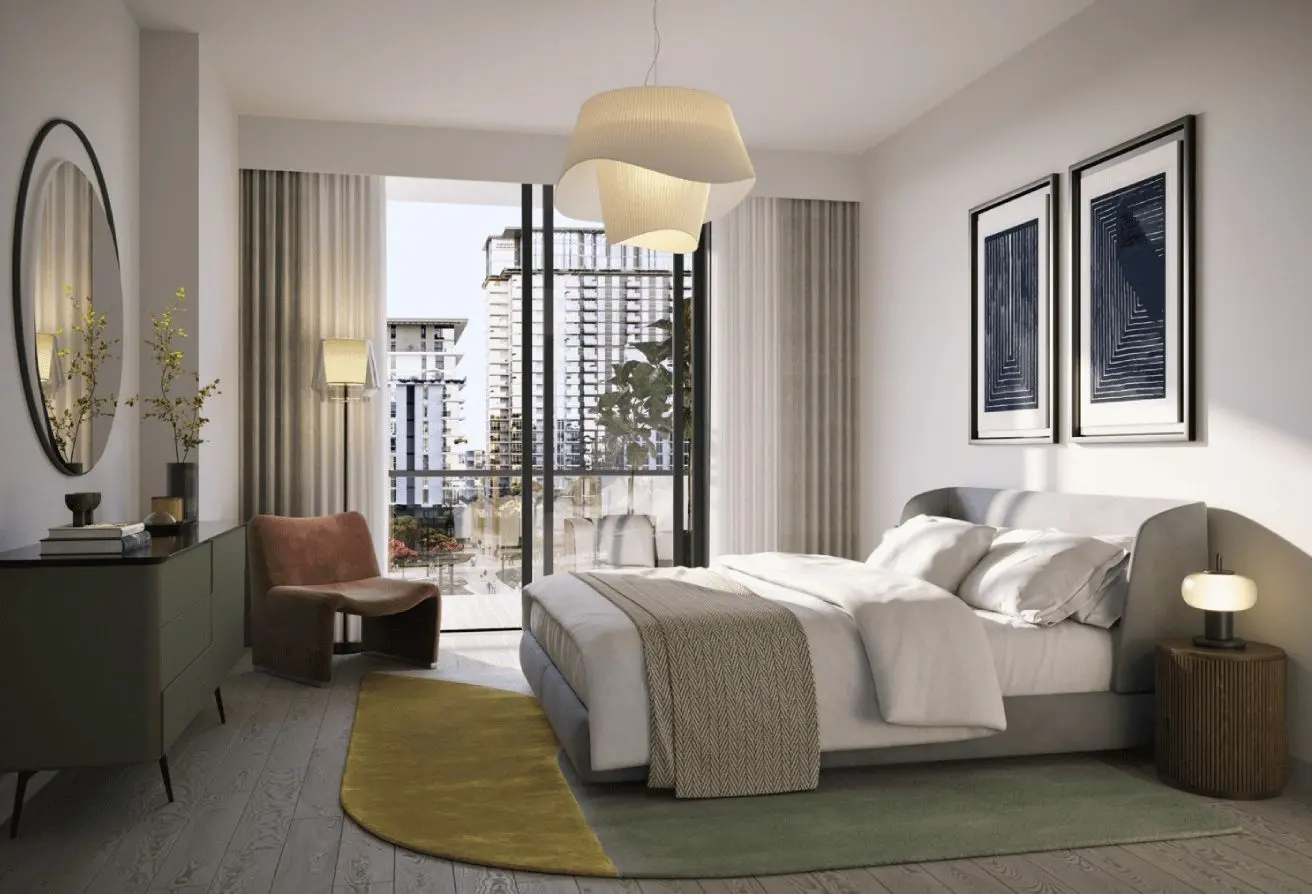 Modern bedroom with a low bed, white linens, and beige throw; doors open to a city-view balcony behind sheer curtains.