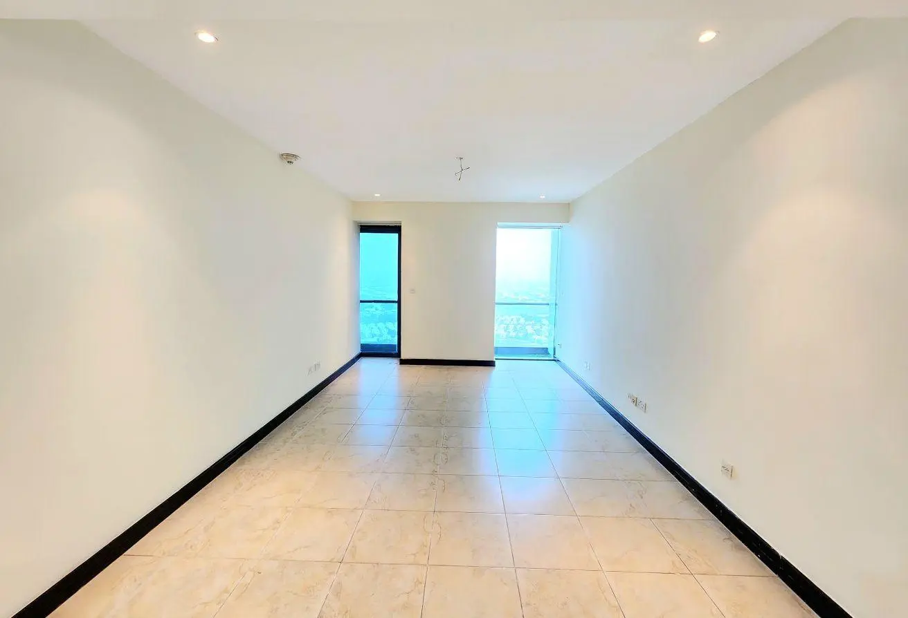 Bright empty living room with white walls, beige tile floor, and a balcony door/window at the far end.