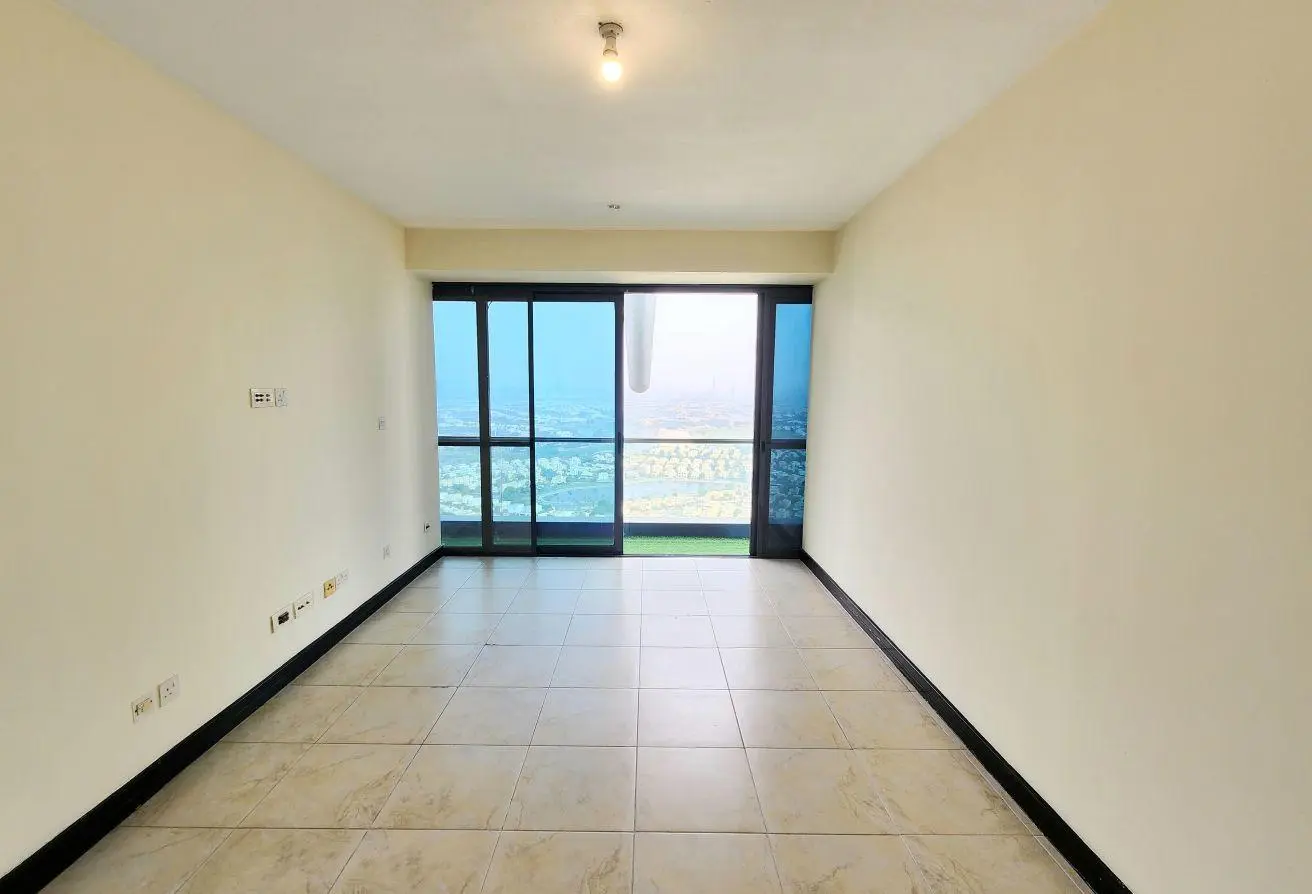 Empty rectangular room with tiled floor, white walls, and a large glass sliding door opening to a balcony with a city view.